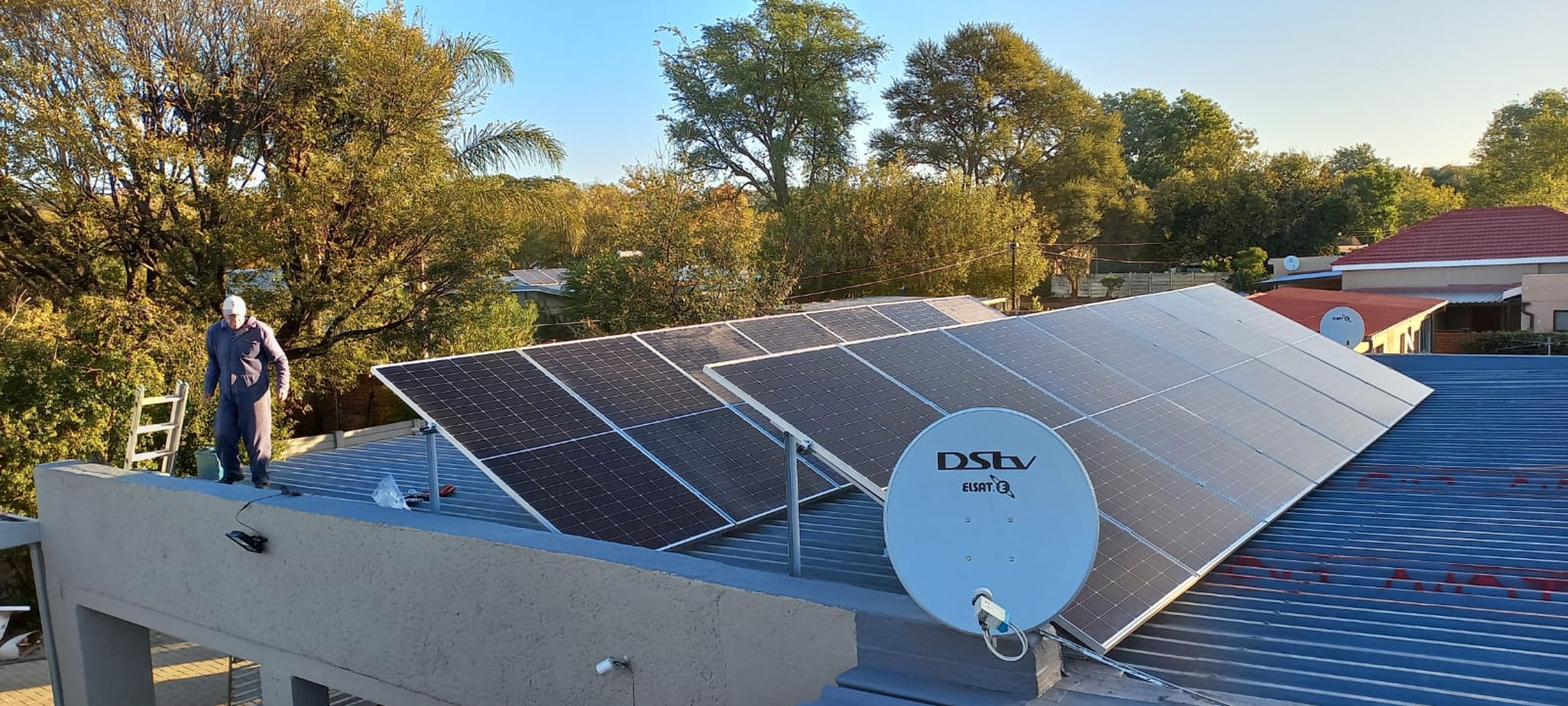 Solar panel installation on residential roof with technician working on photovoltaic system.